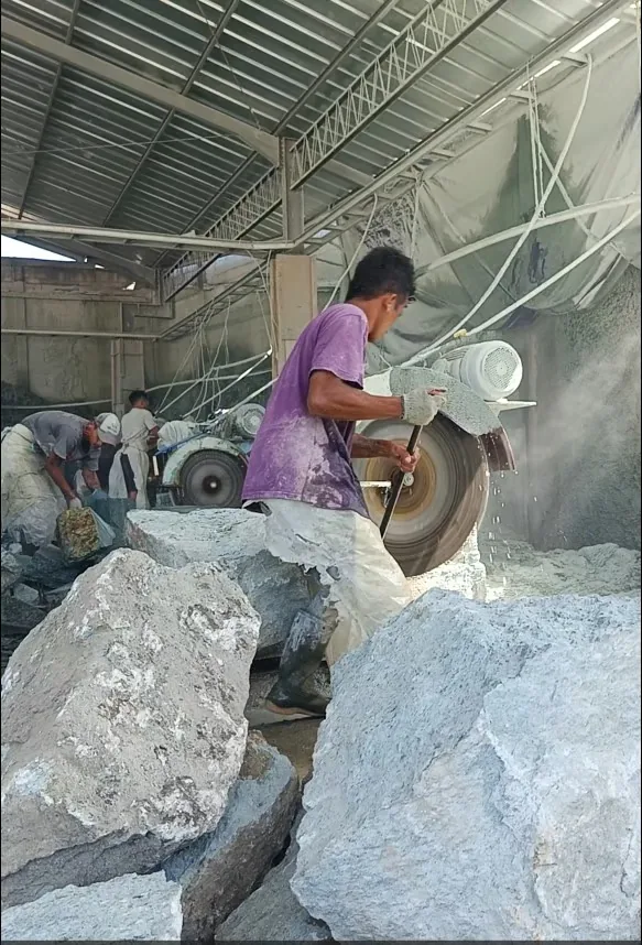 Workers cutting large natural stone blocks with a stone saw